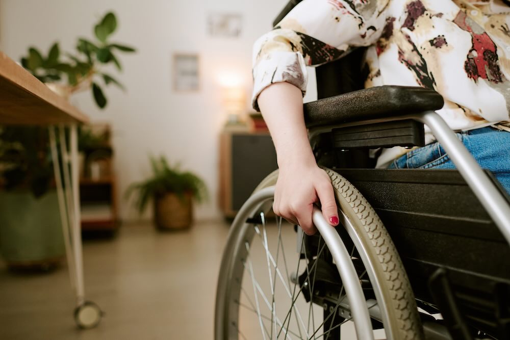 Caucasian young adult woman with disability sitting in wheelchair indoors