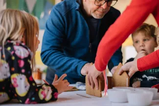 two person making gingerbread house and three children watching them by Phillip Goldsberry courtesy of Unsplash.